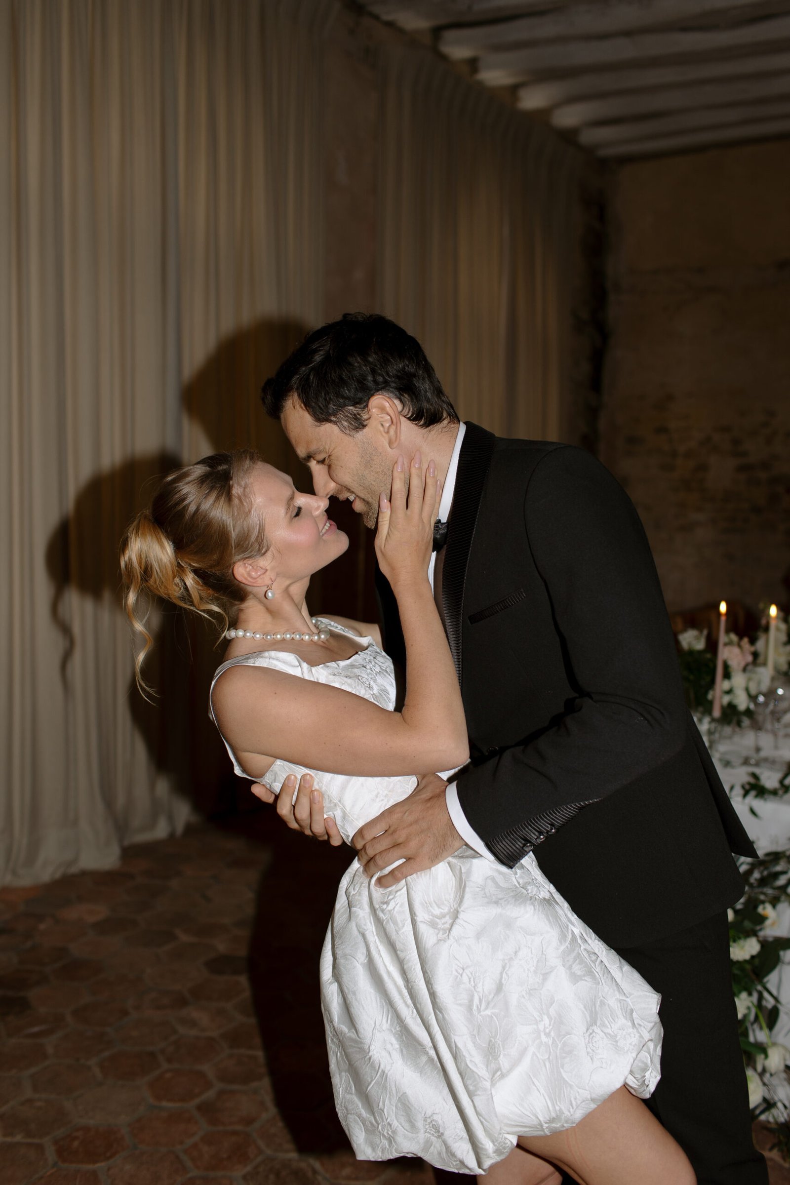 A bride and groom share a romantic moment, embracing closely and gazing into each others eyes on their wedding day.