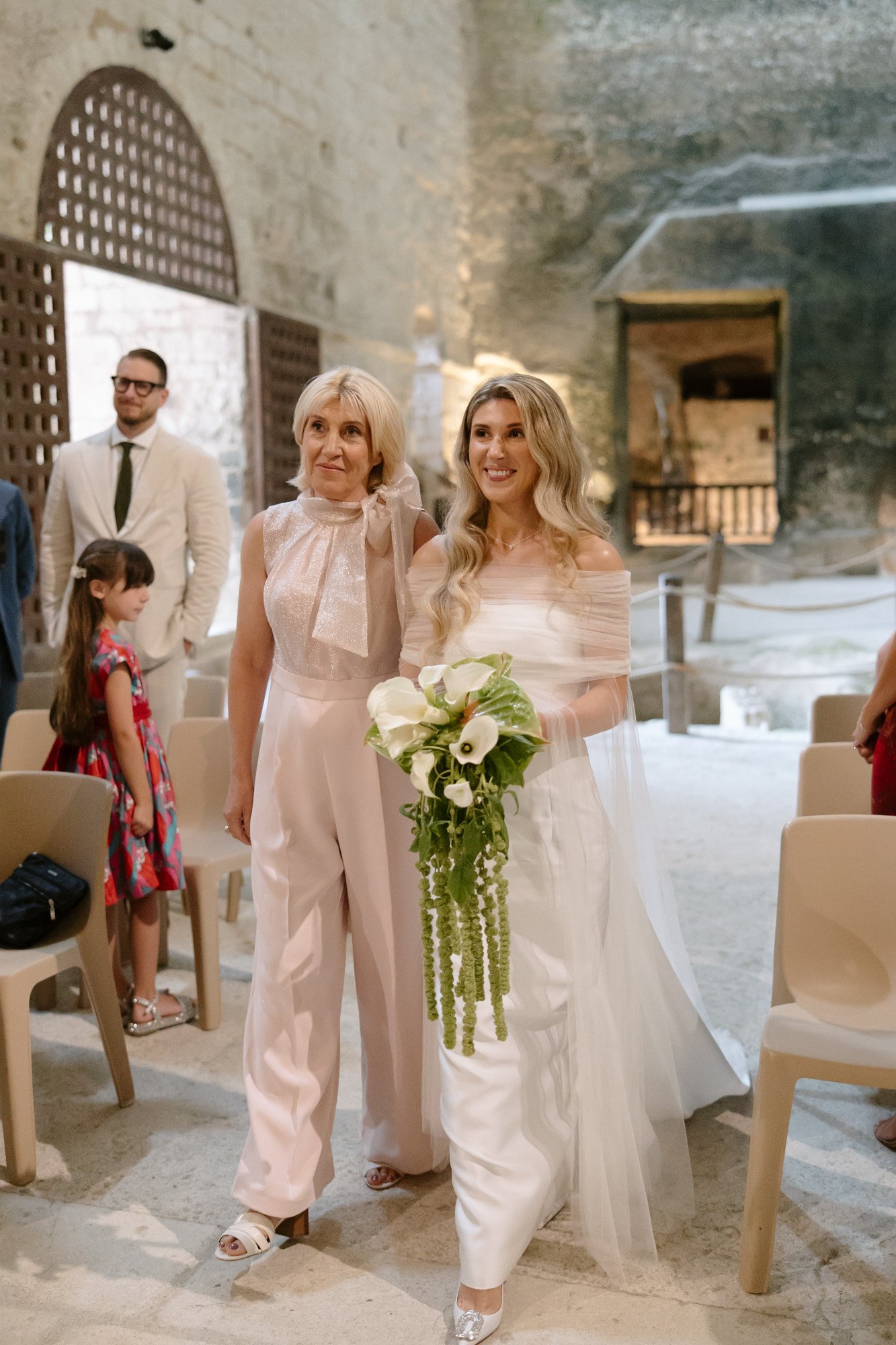 A woman in white dress holding a bouquet of flowers.