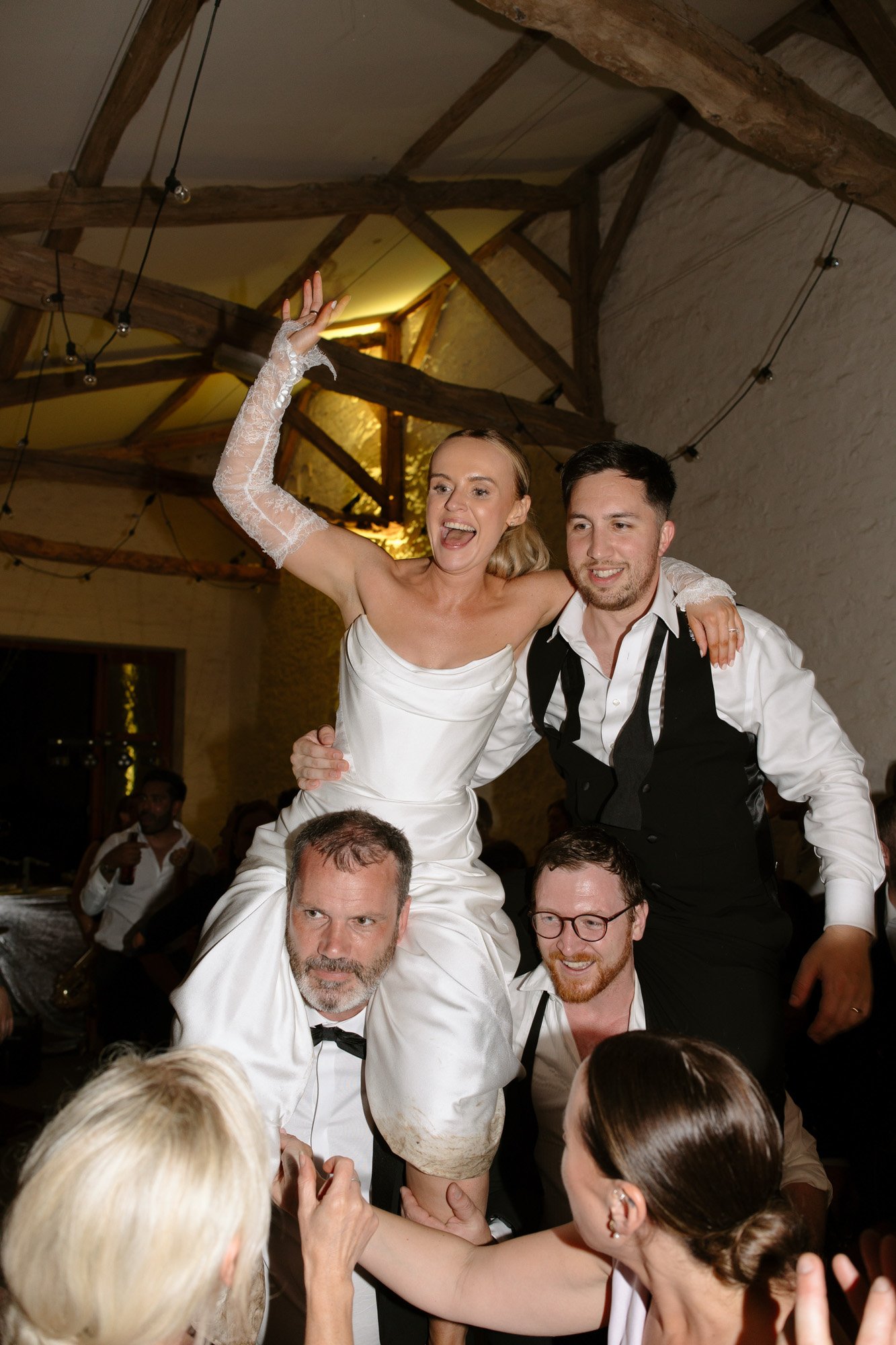 A woman in a white dress with two men in a room with a wood beam. Chateau de la Bourlie wedding.