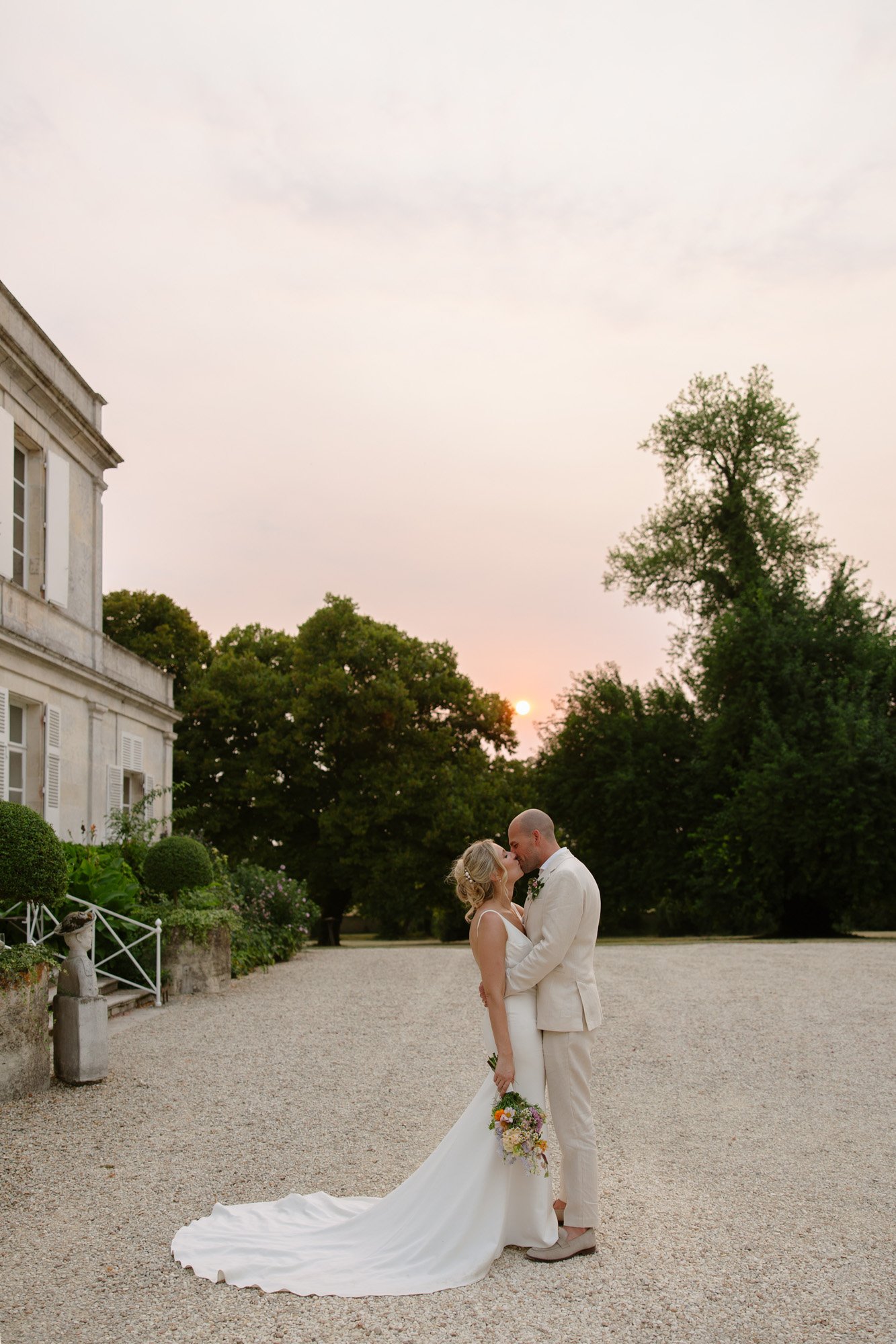 A man and woman kissing in front of a building.  Captured by Cognac wedding photographer.