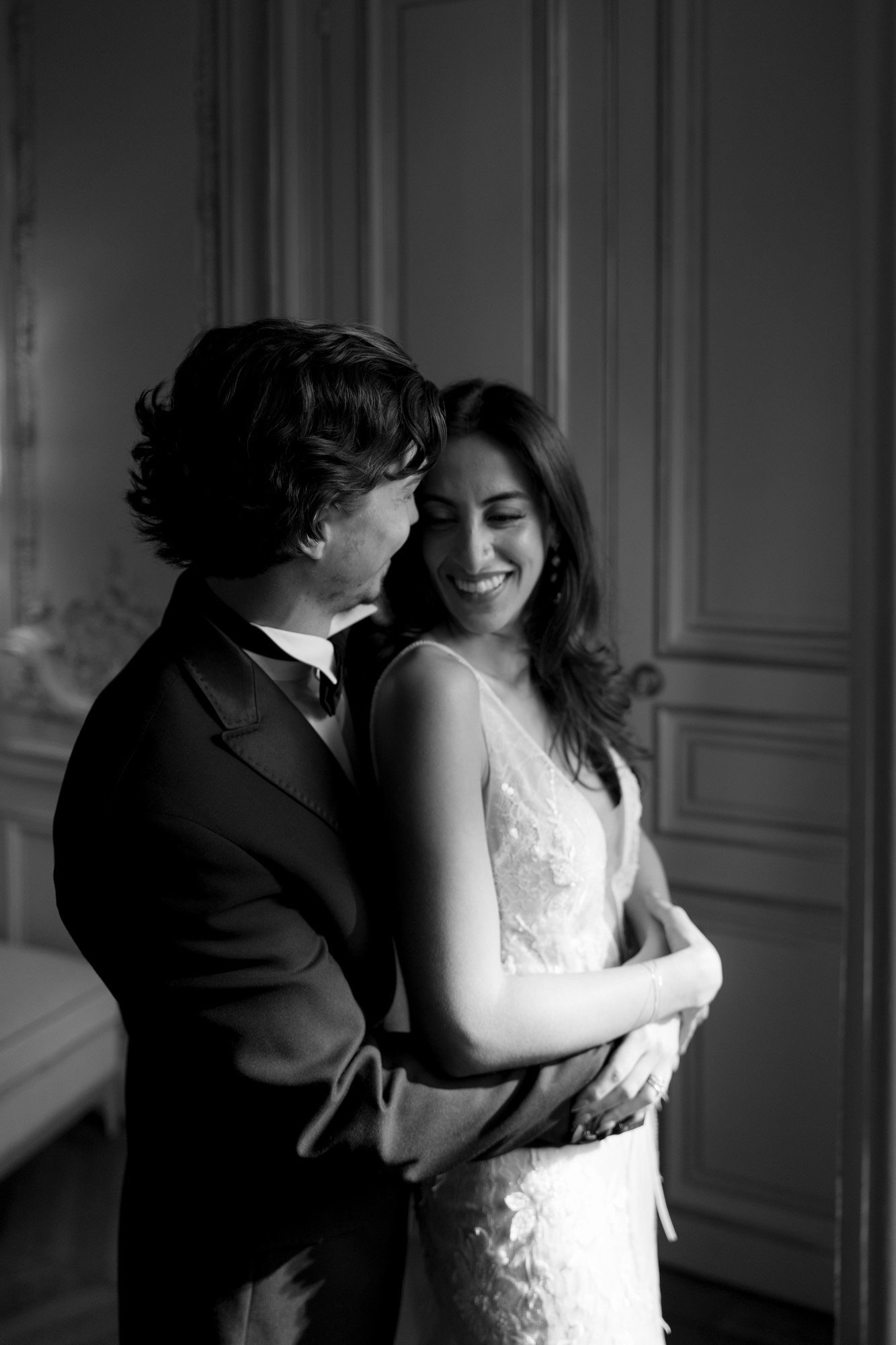 A couple dressed formally stands indoors, embracing and smiling at each other in soft, natural light. Hotel Alfred Sommier Elopement.
